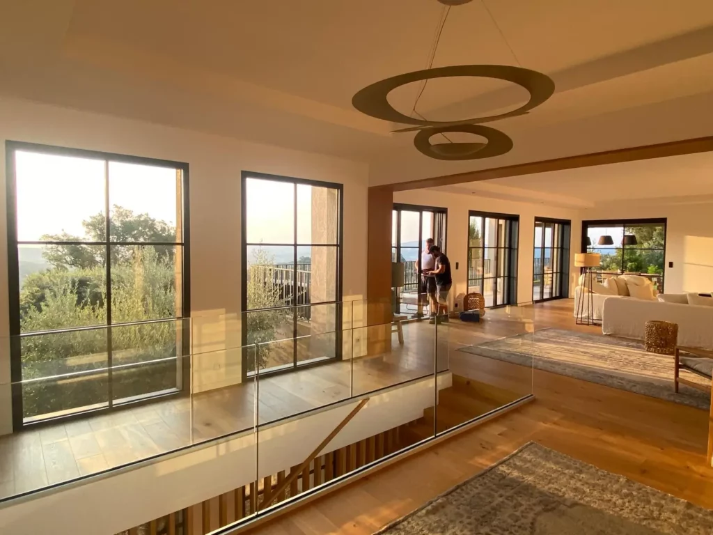 Vue intérieure du grand salon avec baies vitrées coulissantes aluminium et garde-corps en verre lors d'un contrôle de maintenance à Grimaud.