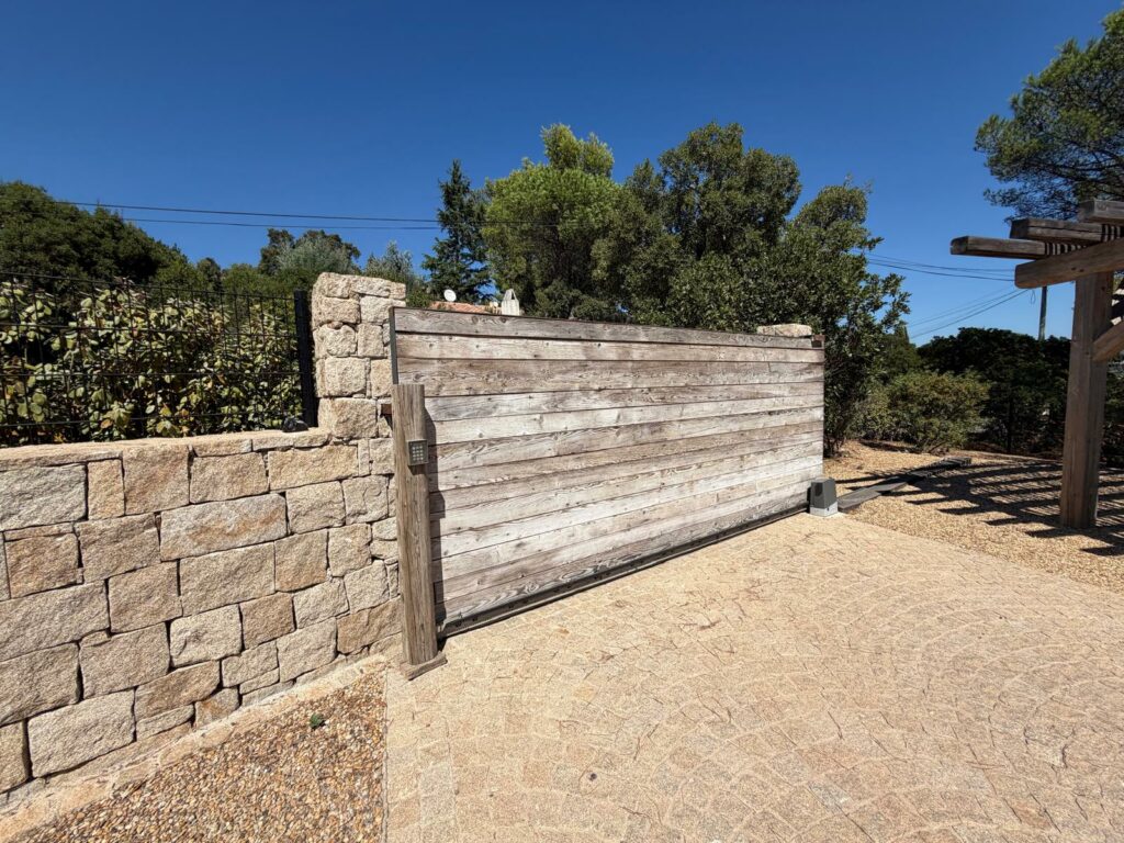 Portail et clôture sur-mesure à Saint-Tropez avec portail coulissant motorisé en bois et mur en pierre