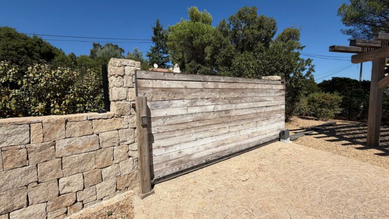 Portail et clôture sur-mesure à Saint-Tropez avec portail coulissant motorisé en bois et mur en pierre