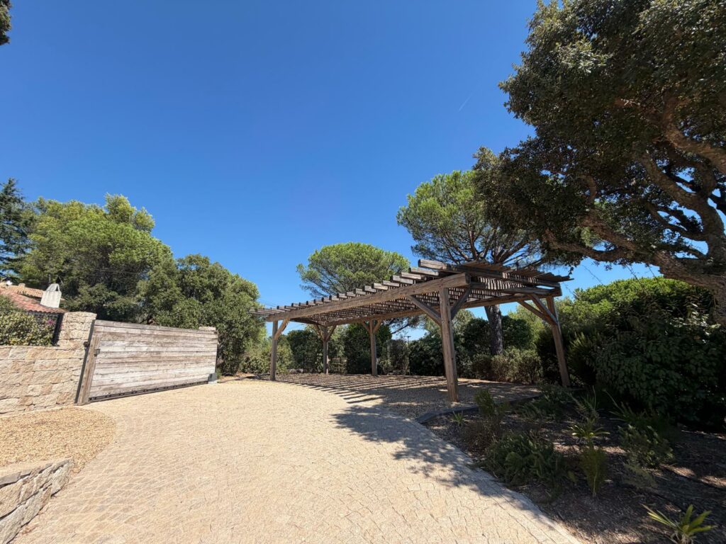 Aménagement d'entrée avec carport pergola en bois et portail motorisé à Saint-Tropez.