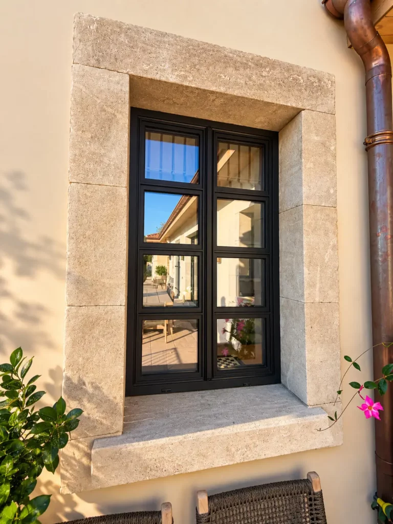 Fenêtre alu noire avec petits bois encadrée de pierre de taille dans une villa à Saint-Tropez