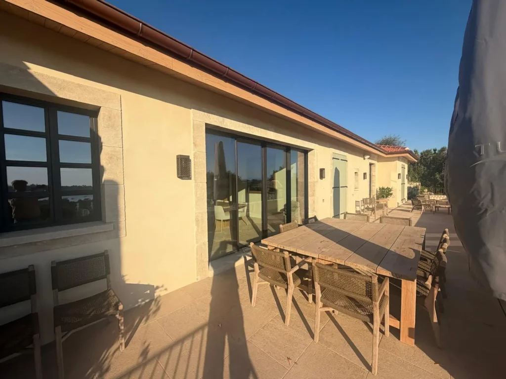 Terrasse de villa varoise avec baie coulissante en aluminium noir et fenêtre à petits bois encadrées de pierre claire
